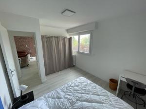 een witte slaapkamer met een bed en een raam bij Urban loft Lorient centre in Lorient