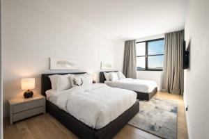 biała sypialnia z 2 łóżkami i oknem w obiekcie Horizon 306/Spacious Penthouse with View w mieście Mont-Tremblant