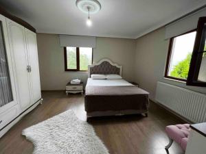 1 Schlafzimmer mit einem Bett, 2 Fenstern und einem Teppich in der Unterkunft Doğa içinde şehir merkezinde in Yomra