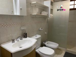 ein Badezimmer mit einem weißen Waschbecken und einem WC in der Unterkunft Una casa amplia y centrica in Tunuyán