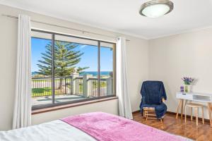 een slaapkamer met een bed en een raam met uitzicht op de oceaan bij Beach Delight: A beach front home with scenic views in Port Noarlunga South