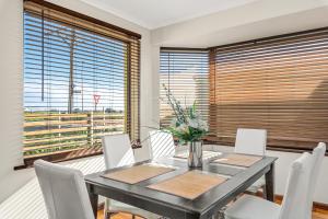 een eetkamer met een tafel en witte stoelen bij Beach Delight: A beach front home with scenic views in Port Noarlunga South