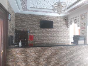 Habitación con pared de ladrillo y TV. en Riad Rayan's Guests, en Marrakech