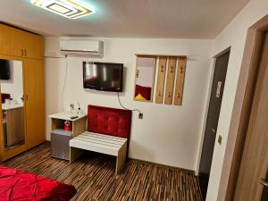 a room with a red chair and a tv on the wall at Casa Laur in Sulina