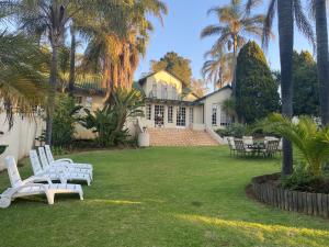 ロードポートにあるSafari Deluxe Rooms - elegant rooms with access to beautiful garden & poolの庭に白いベンチが2つある家