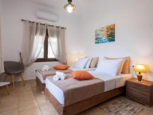 a bedroom with two beds with orange and white pillows at Atalanti Seaside Junior Suites in Keratokampos