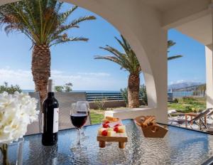 uma mesa com um copo de vinho e uma bandeja de frutas em Atalanti Seaside Junior Suites em Keratokambos