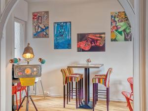 Zimmer mit einem Tisch und Stühlen sowie Gemälden an der Wand in der Unterkunft @ Home Hotel Locarno in Locarno