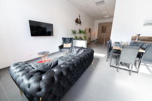 sala de estar con sofá de cuero y comedor en LOFT LA MINE D'OR - Parking gratuit et privé - Wifi - Tout équipé - Machine à laver, en Rive-de-Gier