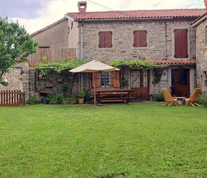 a house with a picnic table and an umbrella in a yard at Pri kovačih, Istra autentica in Movraž