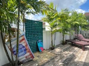 een patio met palmbomen en een surfplank tegen een muur bij 拉威查龙山顶大佛三卧泳池别墅Thaiya Villa in Ban Klang