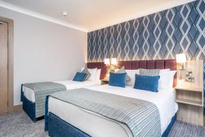 2 Betten in einem Hotelzimmer mit blauen Kissen in der Unterkunft Rochestown Lodge Hotel in Dun Laoghaire