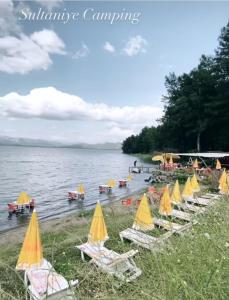 穆拉的住宿－Köyceğiz Sultaniye Camping，海滩上一组带黄伞的草坪椅