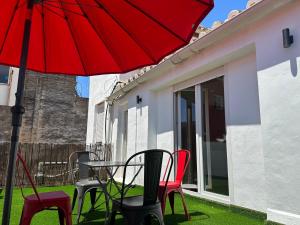 Malaga City Suites في مالقة: طاولة وكراسي مع مظلة حمراء