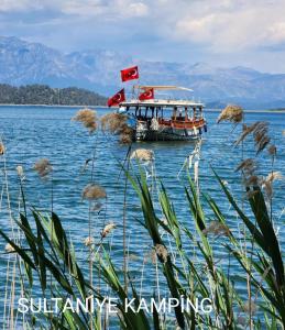 un barco en el agua con banderas. en Köyceğiz Sultaniye Camping, en Muğla