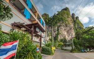 a building with a flag in front of a mountain at Aonang Silver Orchid Resort in Ao Nang Beach