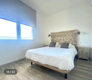 a white bedroom with a large white bed and a window at Sunset view * Swimming pool* A/C in Tarifa