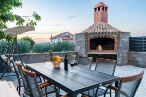 a table and chairs with a fireplace on a patio at Apartment Miruna s bazenom i jakuzijem in Donje Raštane