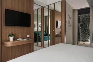 una camera da letto con TV su una parete in legno di Parioli Hotel Rimini a Rimini