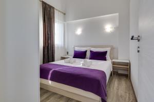 a bedroom with a large bed with purple sheets at Apartment Miruna s bazenom i jakuzijem in Donje Raštane +37 photos