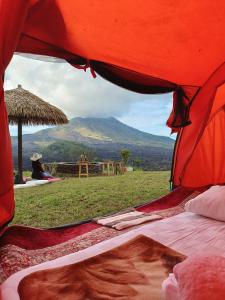 a woman sitting in a tent with a view of a mountain at Kintamani Adventures 'Life Hurt, Nature Heal' in Kintamani
