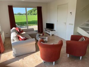 a living room with a couch and two chairs and a television at Gastenverblijf WeijdeBlik in Sinderen