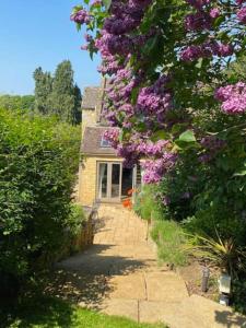 uma casa com flores roxas ao lado em Character Snowshill Cottage - 2 Glebe Cottage’s em Snowshill