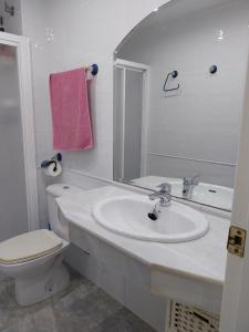 ein Badezimmer mit einem Waschbecken, einem WC und einem Spiegel in der Unterkunft Azahar II Solo Familias Serviplaya in Casas Las Basas