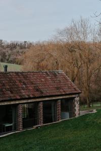 ein altes Backsteinhaus mit Bäumen im Hintergrund in der Unterkunft The Cotswold Farm Hideaway in Alderley