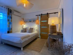 ein Schlafzimmer mit einem Bett und einem Tisch mit einer Lampe in der Unterkunft Hôtel Le Neptune en Camargue in Saintes-Maries-de-la-Mer