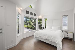 Dormitorio blanco con cama y ventanas en Oswego Paradise Retreat, en Victoria