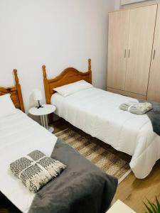 a bedroom with two beds and a night stand at Apartamento Ruiz Zorrilla in Santander
