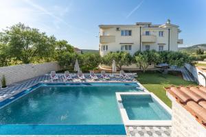 a swimming pool with chairs and a house at Apartment Miruna s bazenom i jakuzijem in Donje Raštane