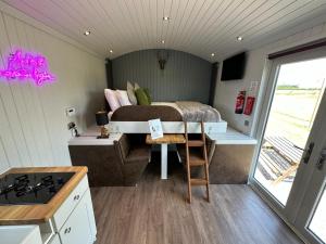 a small bedroom with a bed and a table at The Stag's Head - Shepherds Hut in Great Singleton