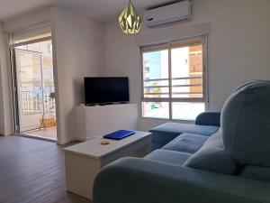 ein Wohnzimmer mit einem blauen Sofa und einem TV in der Unterkunft Amplio piso con terraza a 50 m de playa Miramar in Miramar