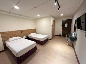 a hotel room with two beds and a television at CU Boutique Hotel in Kota Kinabalu