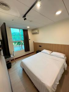 a bedroom with a large white bed and a television at CU Boutique Hotel in Kota Kinabalu