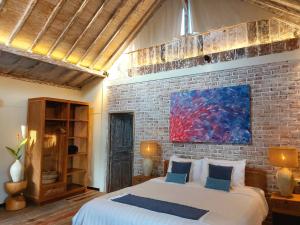 a bedroom with a large bed and a brick wall at Spaces Bali Unique Boutique Hotel in Munggu