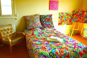1 dormitorio con 1 cama colorida y 1 silla en Warm ART room at home., en Ylitornio
