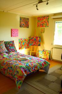 1 dormitorio con 1 cama con sábanas coloridas y cuadros en la pared en Warm ART room at home., en Ylitornio