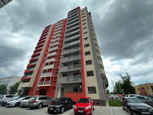 een hoog rood gebouw met auto's geparkeerd op een parkeerplaats bij Renting Solutions Luxury in Iaşi