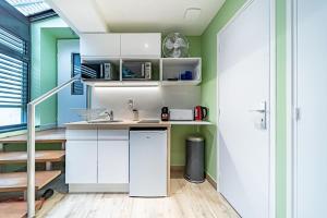 uma cozinha com armários brancos e paredes verdes em Sleep and go -cosy 9 pers-Oullins em Oullins