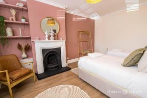 a bedroom with a white bed and a fireplace at Luxury 4-Bed with Garden, WiFi & Parking - Pottery Place in Poole