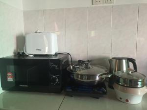 a kitchen with a microwave and two pots and pans at Homey Homestay in Tanjong Sepat