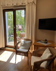 a living room with two chairs and a table and a window at Apartamenty Villa 28 in Pobierowo