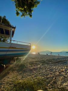 a boat sitting on a beach with the sun setting at Hotel Enseada in São Francisco do Sul