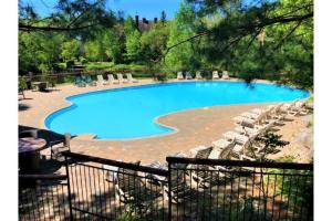 a large swimming pool with chairs and a fence at Plateau 202-5/STUNNING 3bdr with POOL in Mont-Tremblant