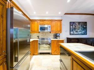 a kitchen with wooden cabinets and a stainless steel refrigerator at Plateau 202-5/STUNNING 3bdr with POOL in Mont-Tremblant