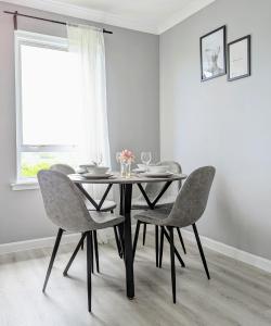 a dining room table with four chairs and a window at Campbeltown View in Campbeltown