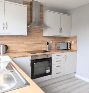 a kitchen with white cabinets and a stove top oven at Campbeltown View in Campbeltown